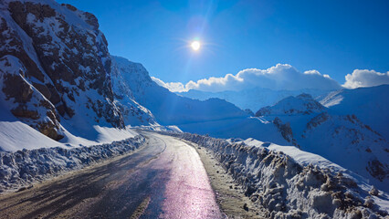 Snowy mountain pass with a winding road, icy edges, rugged peaks, and bright winter sun under a clear blue sky, showing cold alpine conditions.
📍Hazarani, Hawraman Takht 