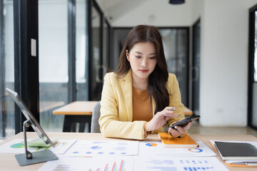Asian businesswoman using smartphone with business analyzing financial charts in the modern office.