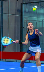 Close-up of a focused female padel player, intently tracking the ball for a forehand shot.