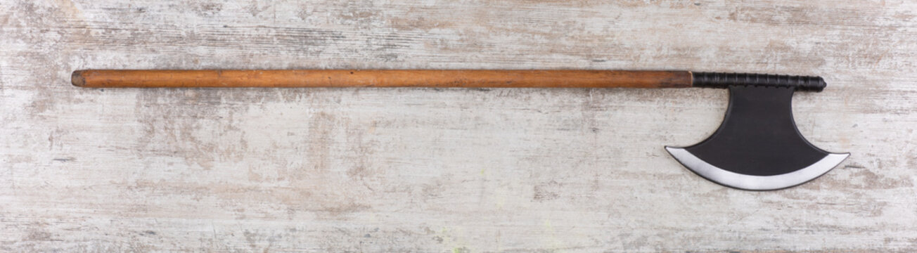 Medieval weapon halberd on wooden background