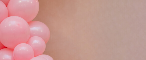 Pastel balloon background with soft pink balloons on beige wall. Minimal festive decoration with copy space, suitable for birthday, baby shower, wedding or celebration design.
