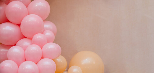 Pastel balloon background with pink and peach balloons on beige wall. Minimal festive decoration with copy space, ideal for birthday, baby shower, wedding or celebration design.
