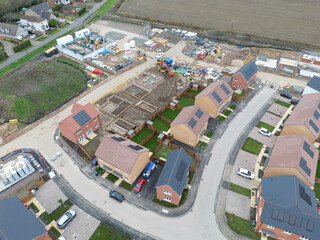 Interesting drone UAV inspection view of newly built homes seen on a sprawling housing development in Britain. Part finished homes can also be seen. Homeowners have moved in.