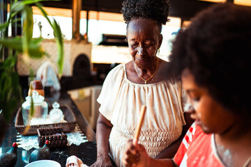 African American grandmother and grandchild cooking together in a cozy home kitchen, sharing culinary traditions.