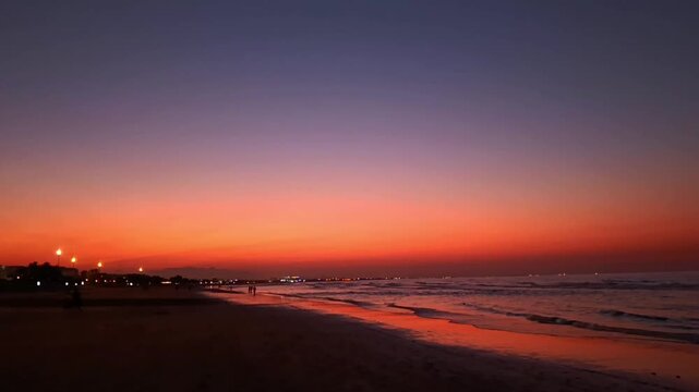 Al Qurum beach at beautiful orange sunset in Muscat, Oman. Hajar mountains seen in the distance