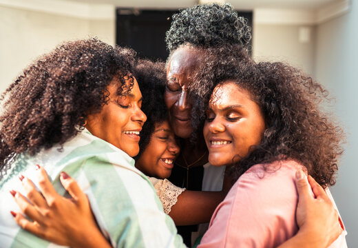 Four happy multi-generational Black women embracing each other with warmth and joy, celebrating family bonds.