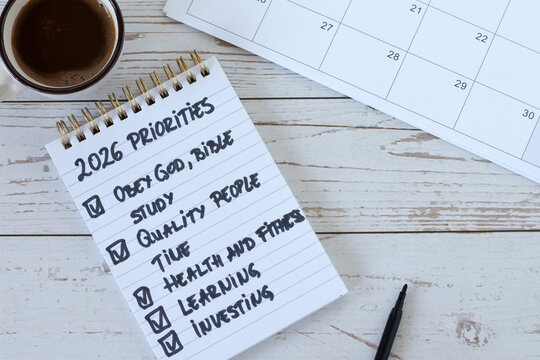 2026 priorities to obey God, bible study, time management, health, learning, investment handwritten text in notebook with calendar and coffee. Top view. Christian to do list, aspirations, and goals.