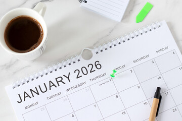 January 2026 new year calendar date with pen, notebook, and coffee cup on a desk. Top view. Annual...