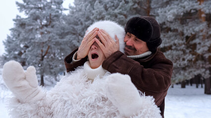 Partners Share Cheerful Moment In Snow, Happy Couple Enjoys Snowy Day With Festive Surprises Amid Sunshine, Joyful Pair Has Fun In Snowy Park With Playful Gestures Under Bright Winter Sun