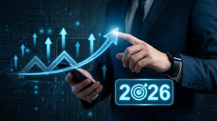 A businessman in a suit touches a glowing upward trending graph representing growth and future financial projections for the year 2026 high quality