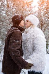 Couple Sharing Tender Snowy Embrace, Romantic Duo Standing Close In Icy Forest Under Sunlight, Blissful Couple Gazing At Each Other Before Exchanging Affectionate Kiss Amid Snow And Sunlight