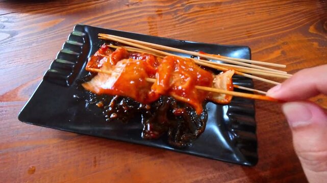 Clip of a hand picking up a dish of fried Korean fish cake or spicy odeng on a bamboo skewer. Videography of Korean fish cake gourmet in 4K HD Resolution