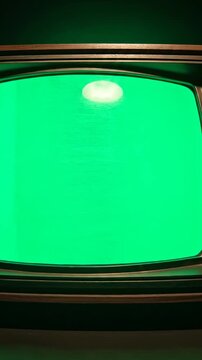 Vintage television set with green screen display on dark green background