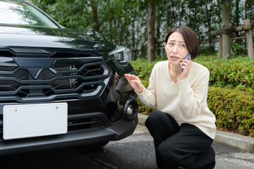 車の前で電話をする女性