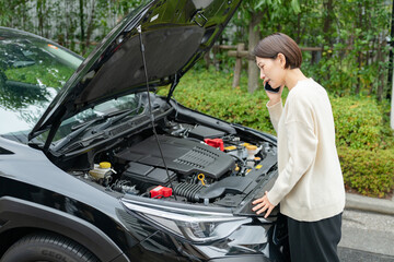 車の前で電話をする女性