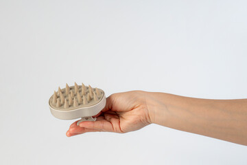 Obraz premium A hair comb used for massaging the scalp while washing hair, held in the hand against a white background.