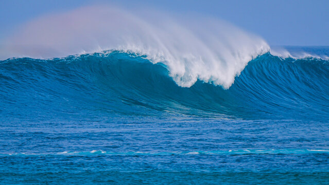 CLOSE UP: Perfect glassy blue wave breaks cleanly under offshore wind, sending spray backward in powerful and elegant arc. Smooth texture and energy of the wave highlight raw beauty of Atlantic Ocean