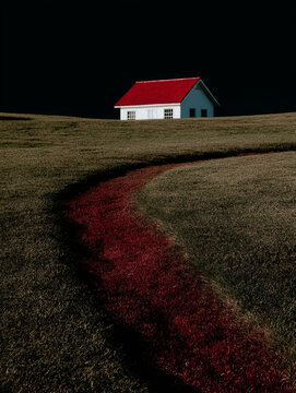 Minimal white house with red roof in open field under dark sky. Concept of solitude, isolation, rural living and real estate lifestyle.