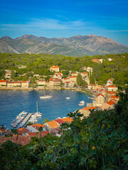 Beautiful bay at Korčula with a coastal village where stone houses with red roofs are nestled between forested hills and blue Adriatic waters. Scenic view while exploring a tourist island in Dalmatia.