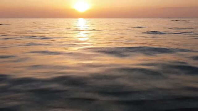 Low Angle Shimmer ocean reflections summer Low angle shot, almost at water level, looking across the expansive ocean as the sun's reflections stretch and dance on the calm summer sea.