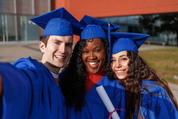 Diverse group of college graduates smiling happy taking a selfie together after ceremony
