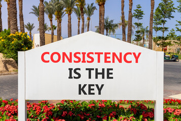 Consistency is the key symbol. Concept words Consistency is the key on beautiful white road sign. Beautiful palm trees blue sky background. Business consistency is the key concept. Copy space.