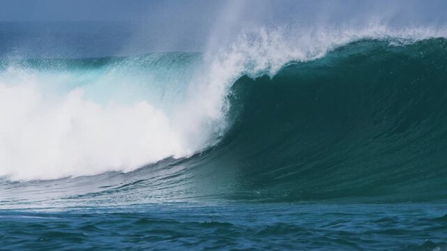 CLOSE UP, SLOW MOTION: Powerful and empty ocean wave crests and breaks under clear blue skies. Perfect shape and offshore spray coming off the lip reflect perfect surf conditions at Canary Islands.