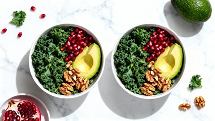 Two cheerful bowls filled with fresh kale, creamy avocado slices, crunchy walnuts, and vibrant pomegranate seeds are placed on a marble countertop, surrounded by ingredients.