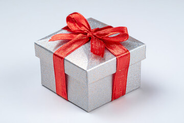 Obraz premium Silver gift box with a vibrant red ribbon, elegantly tied, showcasing a festive design, perfect for celebrations, holidays, and special occasions, adding charm to any event