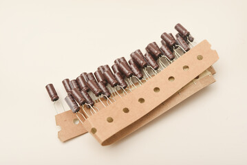 Old capacitors in paper tape. Aluminum capacitors on a white background. The electronic components are in their original packaging.