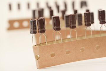 Old capacitors in paper tape. Aluminum capacitors on a white background. The electronic components are in their original packaging.