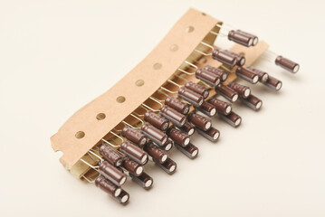 Old capacitors in paper tape. Aluminum capacitors on a white background. The electronic components are in their original packaging.