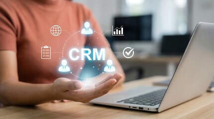 A person interacting with a glowing crm interface projected from their hand showing data analytics and customer relationship management concepts on a laptop