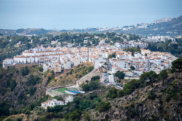Fototapeta premium Scenic view of surrounding mountains and picturesque village from a hiking trail along an old irrigation ditch in Frigiliana, Spain.