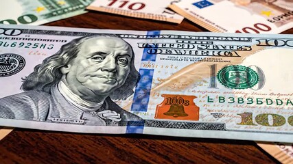 Closeup view of a crisp one hundred US dollar bill featuring Benjamin Franklin prominently displayed amidst a scattering of various international currency notes like Euros symbolizing global finance .