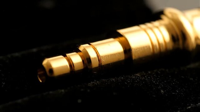 Cinematic macro shot of a golden plug lying on black velvet warm light accentuating fine details enhanced