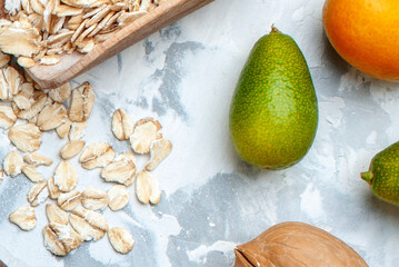 Healthy Breakfast Composition with Raw Oat Flakes Green Avocado and Fresh Orange on Textured Background