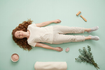 Woman relaxing on floor with spa and wellness accessories for self care