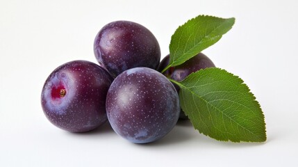 Fresh plums with green leaves on white
