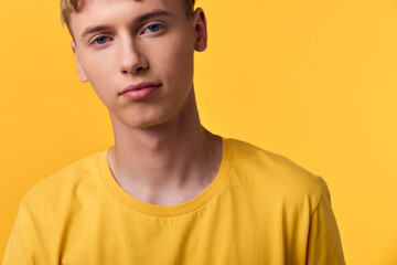 Fototapeta premium Young man wearing a yellow shirt against a bright yellow background, closeup, studio lighting and clean look ideal for fashion, lifestyle and advertising stock, conveying calm, modernity and