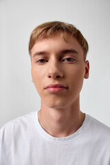 Close up of a young man in a white shirt against a neutral background, studio lighting with calm...