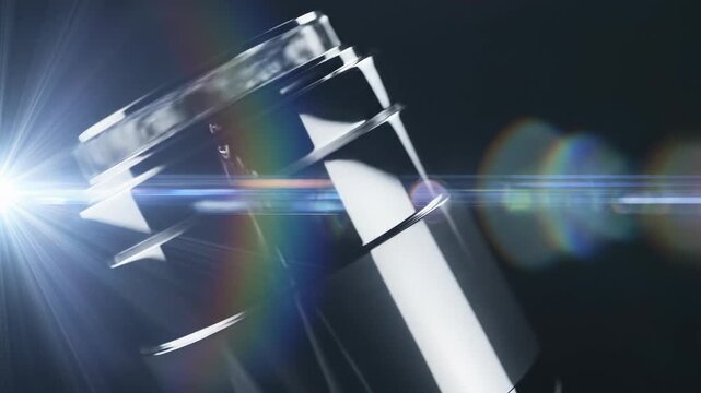 Cinematic abstract close-up shot of a polished metallic cylinder or lens rapidly rotating and reflecting brilliant light creating dynamic lens flares glowing effect, speed, video background