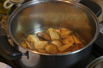 Potato fries sizzling in hot oil in a pan