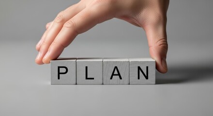 Plan hand block cube Strategic concept portrayed by a hand arranging letter blocks to convey goal setting planning organization and focus with neutral background calm mood