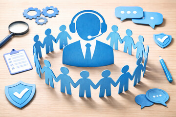Communication customer service teamwork collaboration support trust A blue paper people around a headset operator icon on a wooden desk conveying collaboration support and