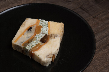 黒い皿に盛り付けられたドライフルーツとナッツが彩る濃厚チーズのテリーヌ