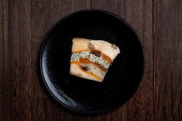 黒い皿に盛り付けられたドライフルーツとナッツが彩る濃厚チーズのテリーヌ