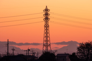 冬の夕焼けに染まる鮮やかなオレンジ色の空と送電線