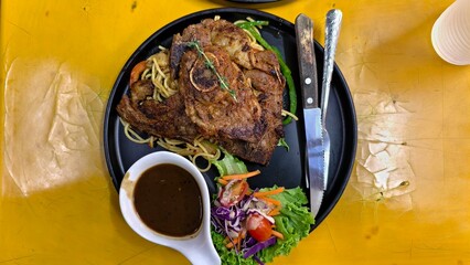 Grilled meat with spaghetti and salad, served with sauce on rustic table, showcasing balanced and...