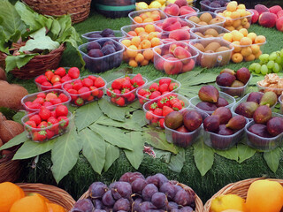 Assortimento di frutta fresca estiva in vaschette su banco del mercato con fragole e fichi 1696